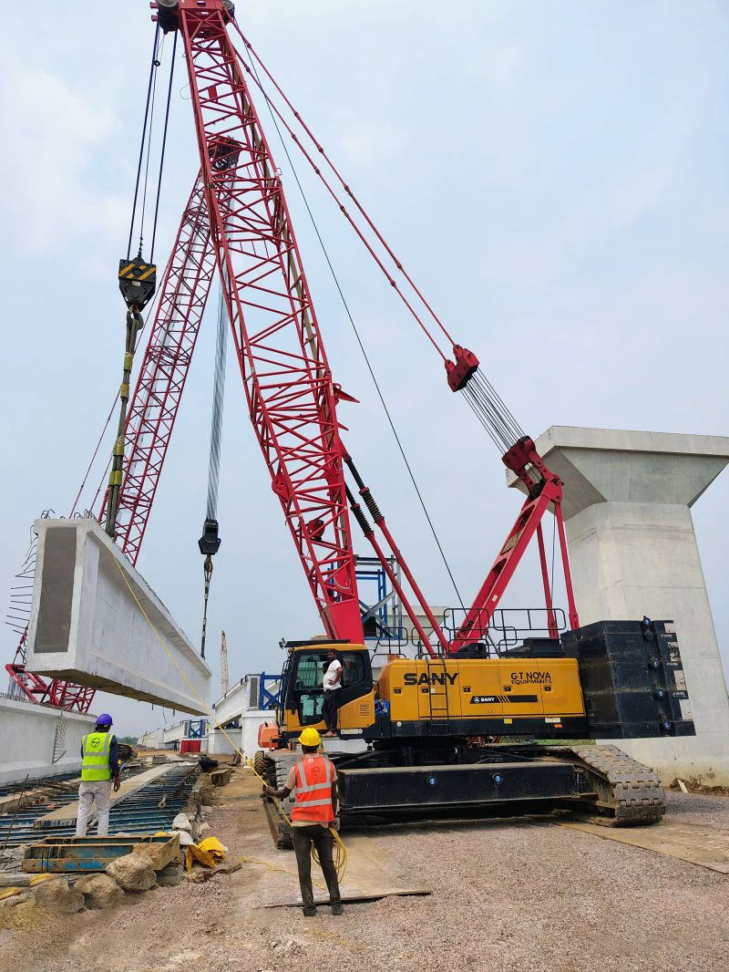 Crawler crane lifting beams at Mumbai metro site with workers around